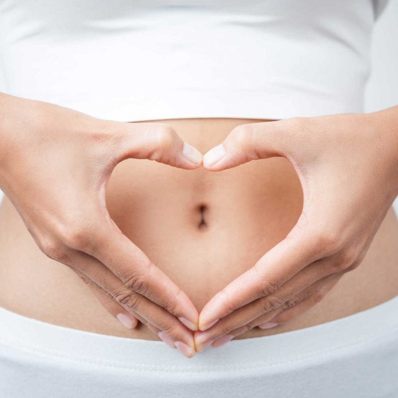 woman making heart with hands in front of stomach